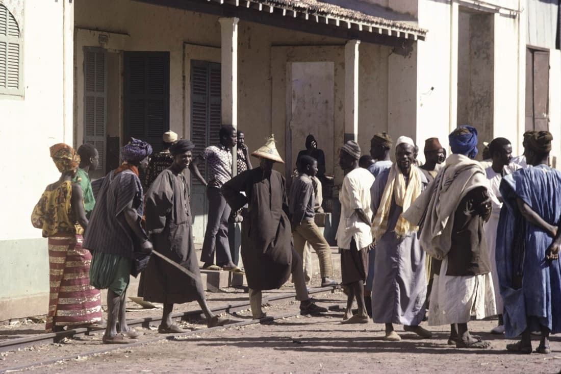 Devant une gare de Dakar, un homme coiffé du chapeau de paille pointu peul.