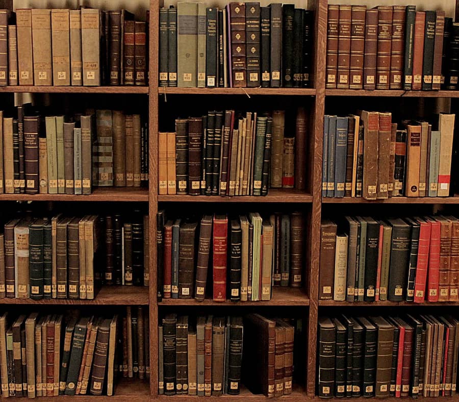 Des rayonnages de bibliothèque garnis de vieux livres reliés : la bibliothèque dont parle la formule.